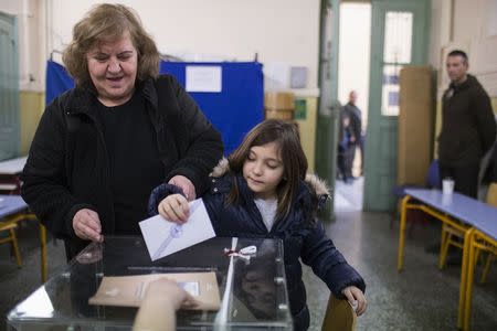 A woman with a child casts her ballot at a polling station in an elementary school during Greece's parliamentary elections in Athens January 25, 2015. REUTERS/Marko Djurica