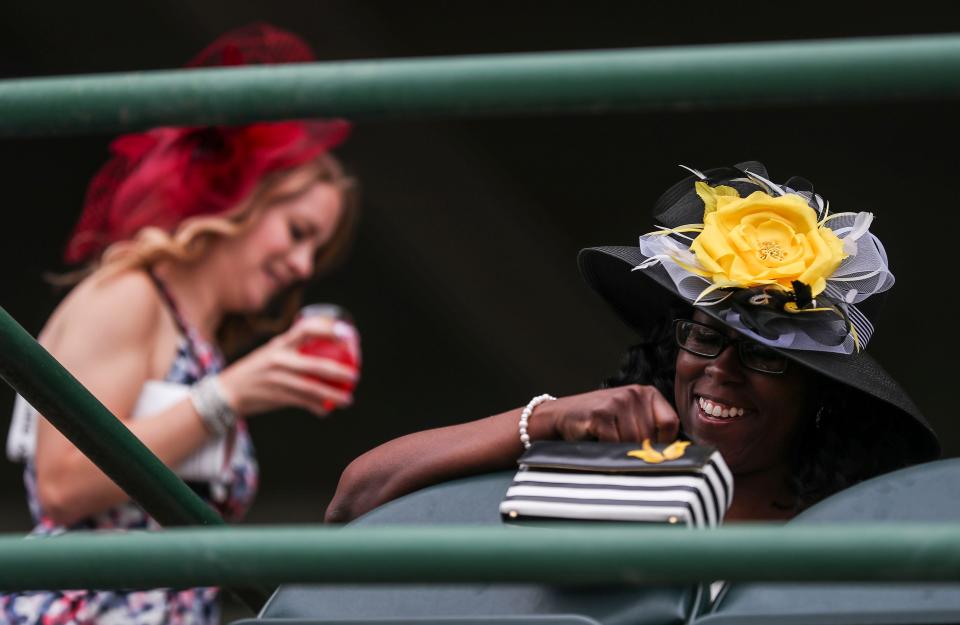 Natosha Cuesta, right, smiles while holding her matching purse while sitting in the Grandstand on Thurby at Churchill Downs.