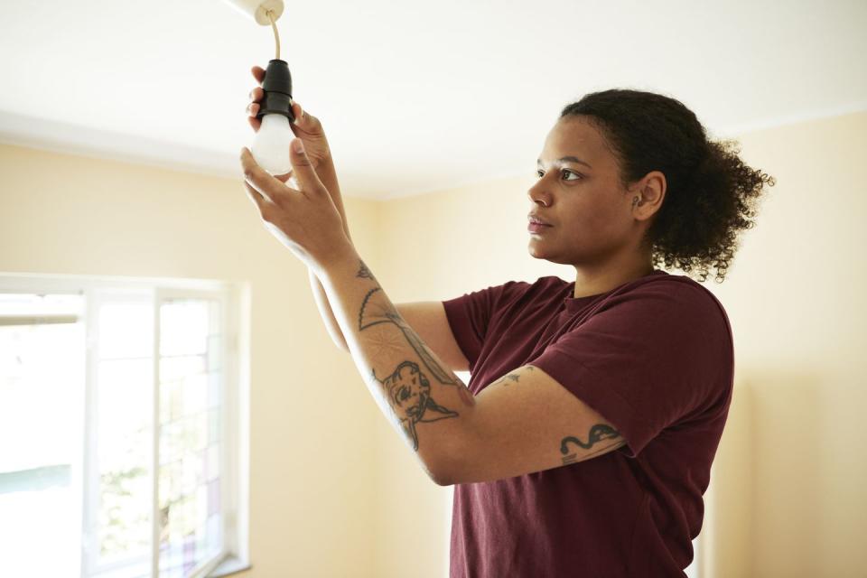 woman changing light bulb in living room