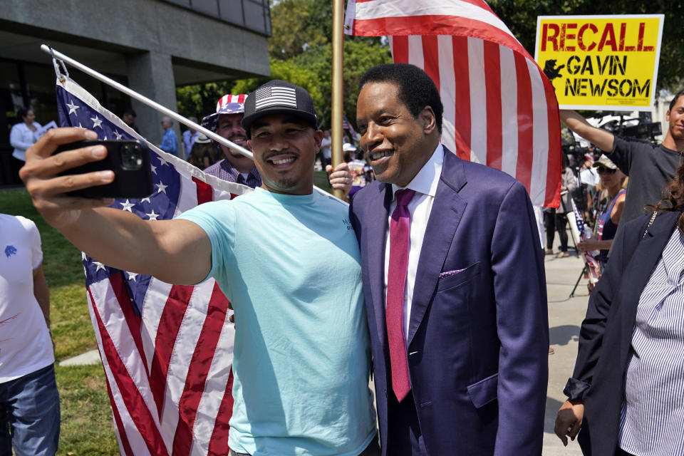 FILE — In this July 13, 2021 file photo, radio talk show host Larry Elder, center, poses for selfies with supporters during a campaign stop in Norwalk, Calif. Alexandra Datig, Elder's former fiancee said Thursday, Aug. 19 that Elder once displayed a gun to her during a heated argument in 2015. Elder said he never brandished a gun at anyone. (AP Photo/Marcio Jose Sanchez, File)