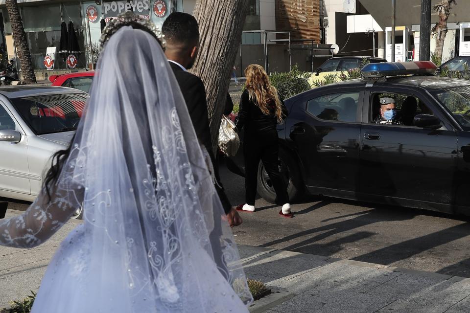 FILE - In this April 18, 2020 file photo, a policeman asks a bride and groom to leave the waterfront promenade where they had decided to take some pictures, in Beirut, Lebanon. In a region where marriage is the cornerstone of society, couples are plowing ahead with weddings, despite the deadly risks. From the Palestinian territories to the United Arab Emirates, officials attribute a spike in coronavirus cases to traditional, large-scale weddings that flout public health restrictions. (AP Photo/Hussein Malla, File)