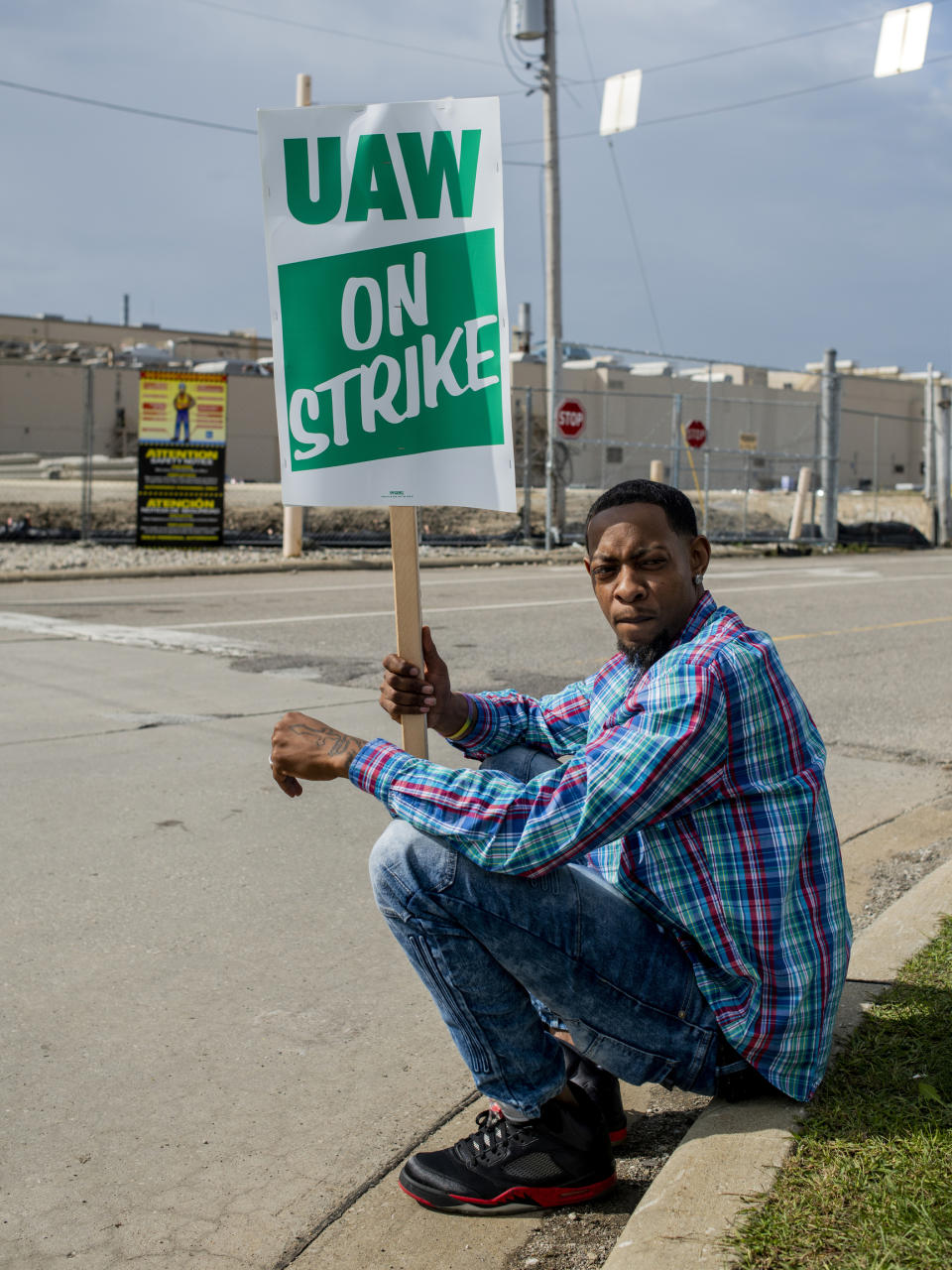 Rory Lee of Flint, Mich., sits on the curb as he protests alongside other General Motors employees outside of the Flint Assembly Plant on Sunday, Sept. 15, 2019 in Flint. GM autoworkers officially go on strike at midnight Sunday after UAW leadership voted to do so Sunday morning. (Jake May/The Flint Journal via AP)