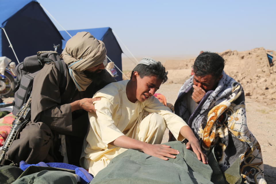 People grieving while covering the body of an earthquake victim.