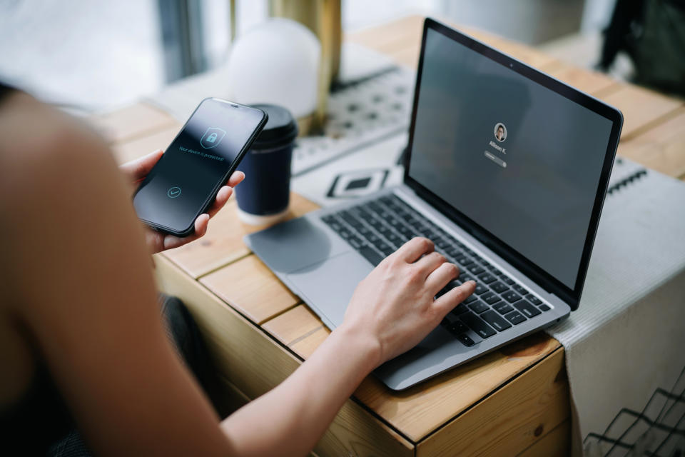 Person using a smartphone to unlock a laptop, implying a focus on technology for wellness or productivity