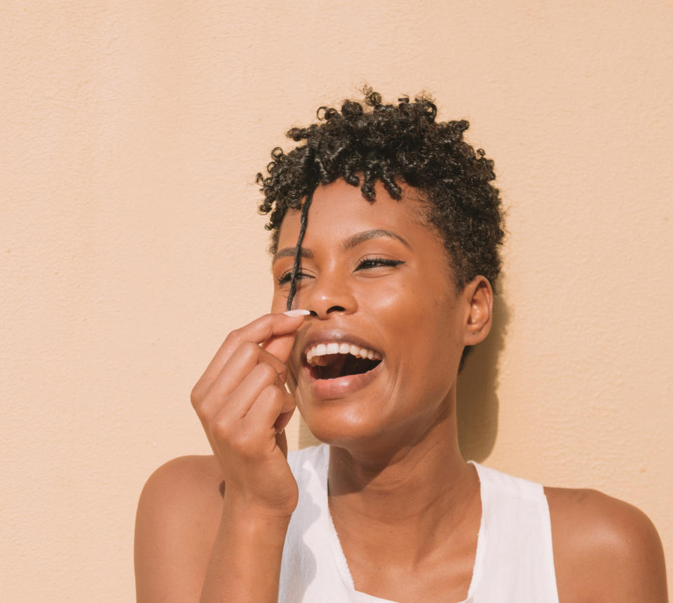 A woman smiling and playing with her hair