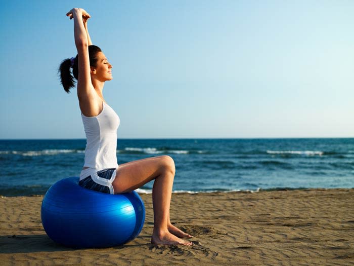 mujer haciendo pilates en la playa