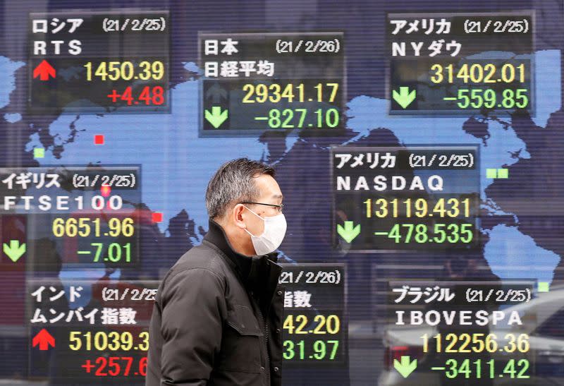 FILE PHOTO: A man walks past a stock quotation board at a brokerage in Tokyo