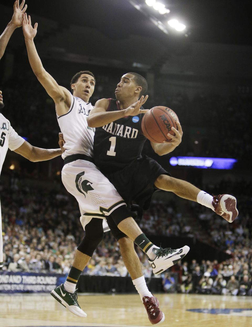 Harvard’s Siyani Chambers (1) passes around Michigan State’s Travis Trice in the second half during the third-round game of the NCAA men's college basketball tournament in Spokane, Wash., Saturday, March 22, 2014. Michigan State won 80-73. (AP Photo/Young Kwak)