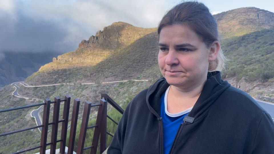 Livia Karczewski, a woman with dark blonde hair, wearing a black hooded top with mountainous terrain visible behind her