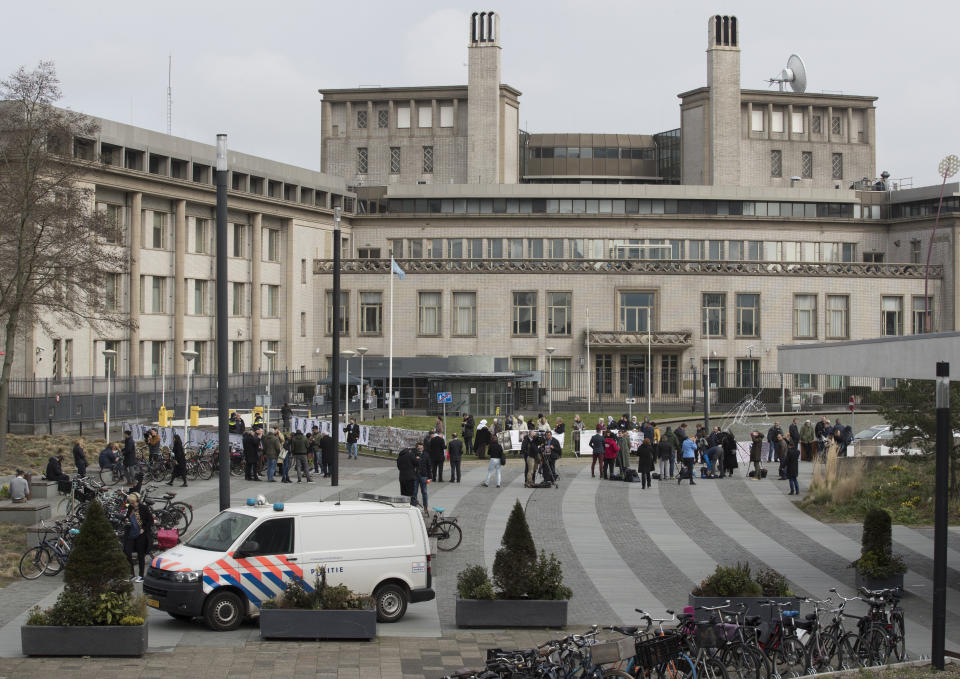 Demonstrators and journalists gather outside the building which houses the International Residual Mechanism for Criminal Tribunals prior to the appeals judgment of former Bosnian Serb leader Radovan Karadzic in The Hague, Netherlands, Wednesday, March 20, 2019. Nearly a quarter of a century since Bosnia's devastating war ended, Karadzic is set to hear the final judgment on whether he can be held criminally responsible for unleashing a wave of murder and destruction. United Nations appeals judges will on Wednesday rule whether to uphold or overturn Karadzic's 2016 convictions for genocide, crimes against humanity and war crimes, as well as his 40-year sentence. (AP Photo/Peter Dejong)