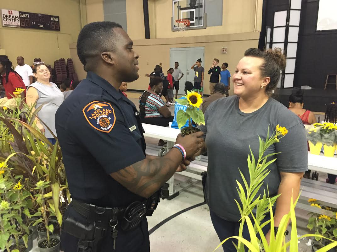 Heather Harris hands Officer Deangelo Anthony a free sunflower at 2016 National Night Out at the Dream Center in Lakeland. File Photo.