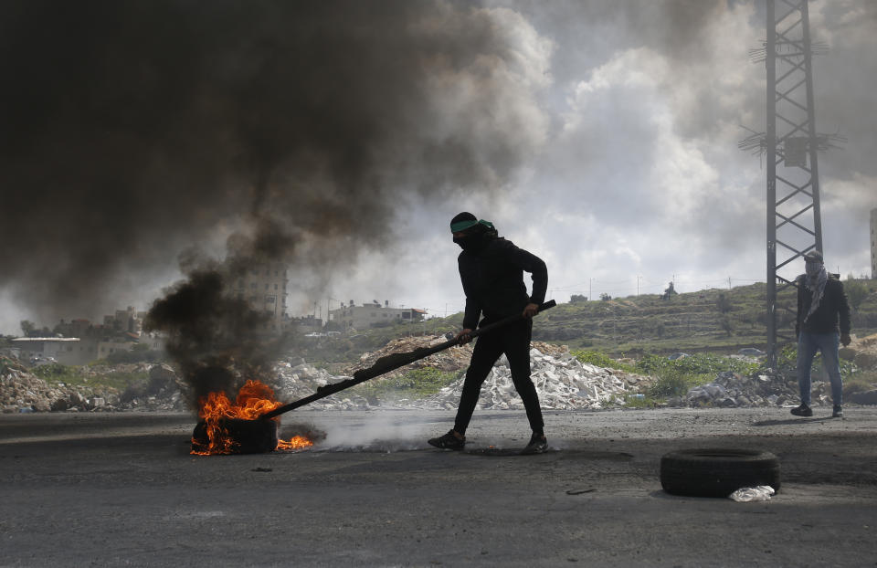 A Palestinian protester burns a tyre during a clashes with Israeli troops during demonstration in support of Palestinian prisoners held in Israeli jails at checkpoint Bet El near the West Bank city of Ramallah , Wednesday, March 27, 2019.(AP Photo/Majdi Mohammed)