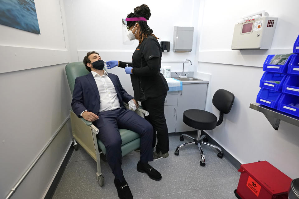 Medical Assistant Aneka Gopaulsingh administers a swab to Julian Bernstein at the new XpresCheck COVID-19 testing facility at Boston Logan International Airport, Wednesday, Oct. 28, 2020, in Boston. The testing site is open for airport and airline employees, and will open to passengers and the general public in mid-November. (AP Photo/Elise Amendola)