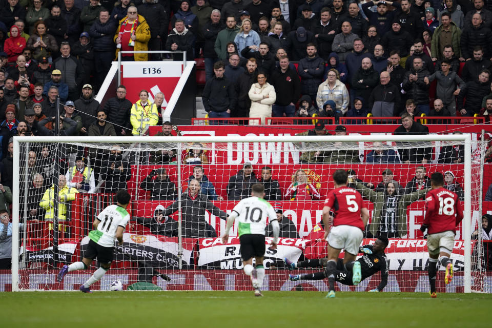 Liverpool's Mohamed Salah, left, scores his side's second goal by a penalty past Manchester United's goalkeeper Andre Onana during the English Premier League soccer match between Manchester United and Liverpool at the Old Trafford stadium in Manchester, England, Sunday, April 7, 2024. (AP Photo/Dave Thompson)