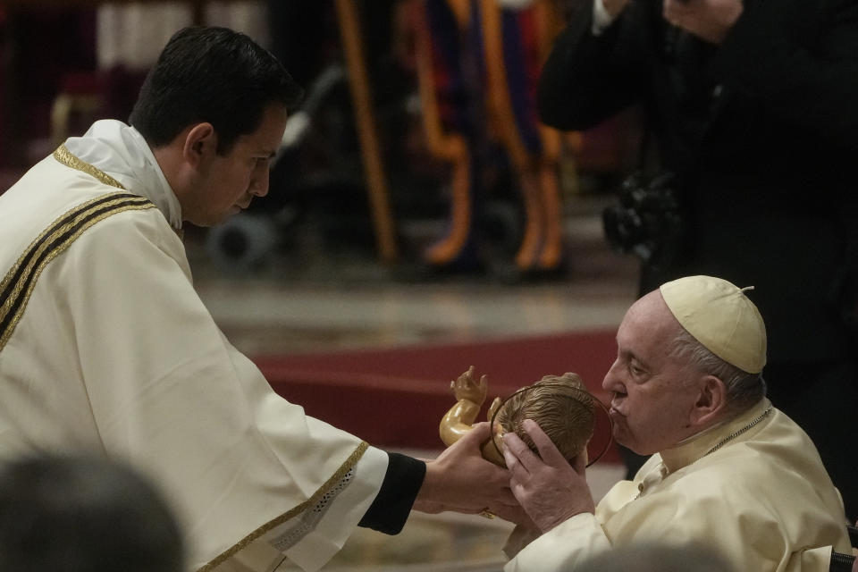 Pope Francis kisses a statue of Baby Jesus as he presides over Christmas Eve Mass, at St. Peter's Basilica at the Vatican, Saturday Dec. 24, 2022. (AP Photo/Gregorio Borgia)