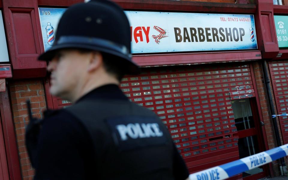 A police officer stands outside a barber's shop in Moss Side which was raided by officers in Manchester - Credit: Darren Staples/Reuters