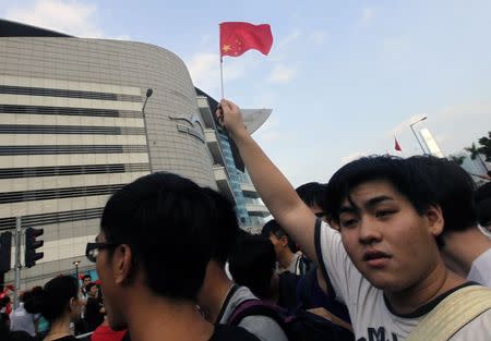 A man holds up a China national flag upside down as he attends a flag raising ceremony in Hong Kong October 1, 2014, celebrating the 65th anniversary of China National Day. REUTERS/Stringer