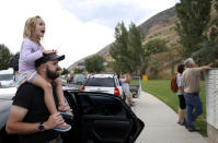 Quinn Smith and her father, David Smith, watch a helicopter take off as firefighters battle a wildfire in Springville on Monday, Aug. 1, 2022. A Utah man has been arrested on accusations he started a wildfire while trying to burn a spider with his lighter. A probable cause statement says 26-year-old Cory Allan Martin told deputies that he spotted the spider Monday while he was in a hiking area in the foothills south of Salt Lake City near the city of Springville. (Kristin Murphy/The Deseret News via AP)