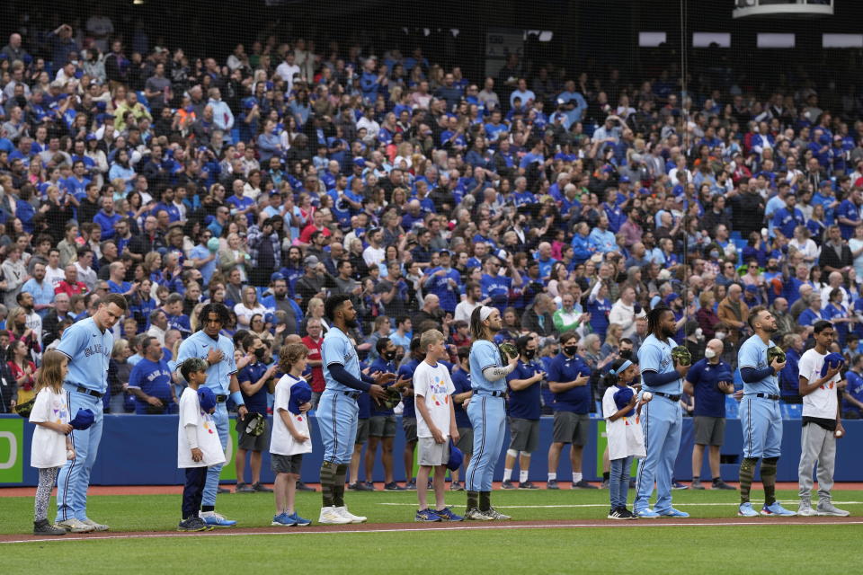 Toronto Blue Jays players stand with children on the third base line during the national anthems prior to playing the Cincinnati Reds in a baseball game in Toronto, Sunday, May 22, 2022. (Frank Gunn/The Canadian Press via AP)