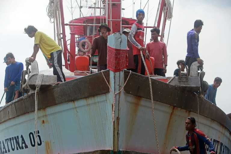 Migrant workers from Myanmar stand on a fishing boat as it arrives at the port in the southern Thai city of Pattani on June 18, 2014