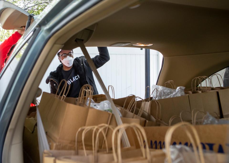 A People’s Liberation Program member, gathers grocery bags together into the car for their free grocery event in Rochester, N.Y. on May 7, 2022.