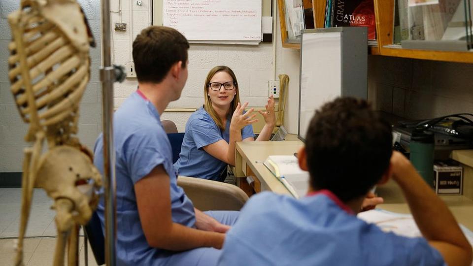 Varios estudiantes de medicina charla en torno a un esqueleto