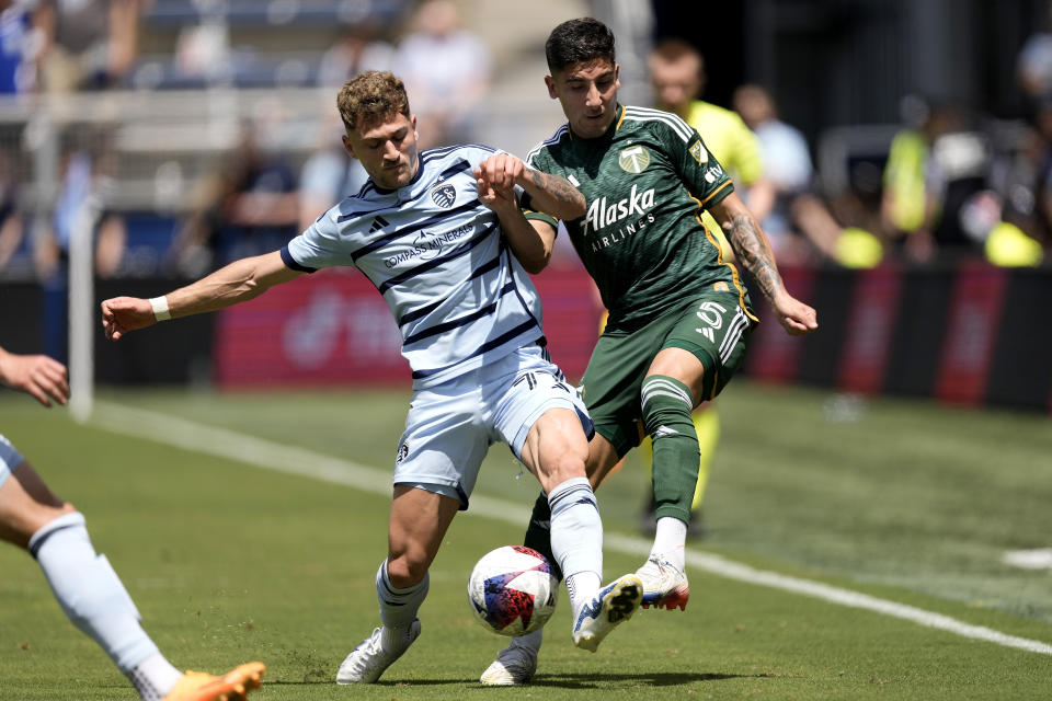 Sporting Kansas City midfielder Marinos Tzionis (77) and Portland Timbers defender Claudio Bravo (5) battle for the ball during the first half of an MLS soccer match Sunday, May 28, 2023, in Kansas City, Kan. (AP Photo/Charlie Riedel)