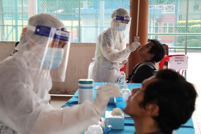 FILE PHOTO: Medical workers collect swab samples from people at a coronavirus disease (COVID-19) testing centre, in Petaling Jaya