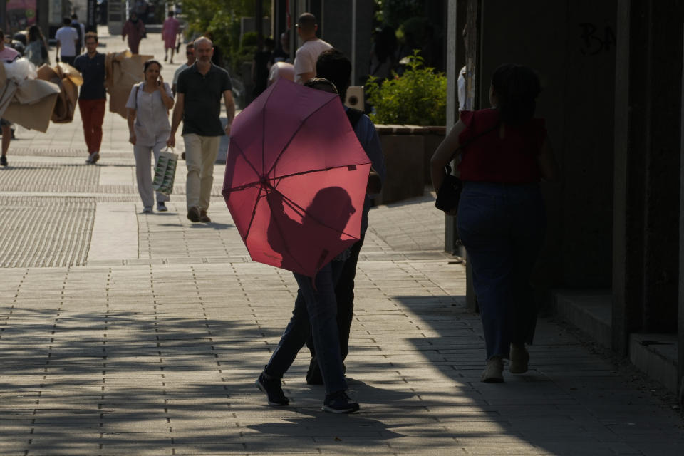 A woman walks with an umbrella to protect against the sun in Madrid, Spain, Wednesday, July 13, 2022. Weather forecasters say Spain is expected to have its second heat wave in less than a month and that it will last at least until the weekend. Meteorologists said an overheated mass of air and warm African winds are driving temperatures in the Iberian Peninsula beyond their usual highs. (AP Photo/Paul White)