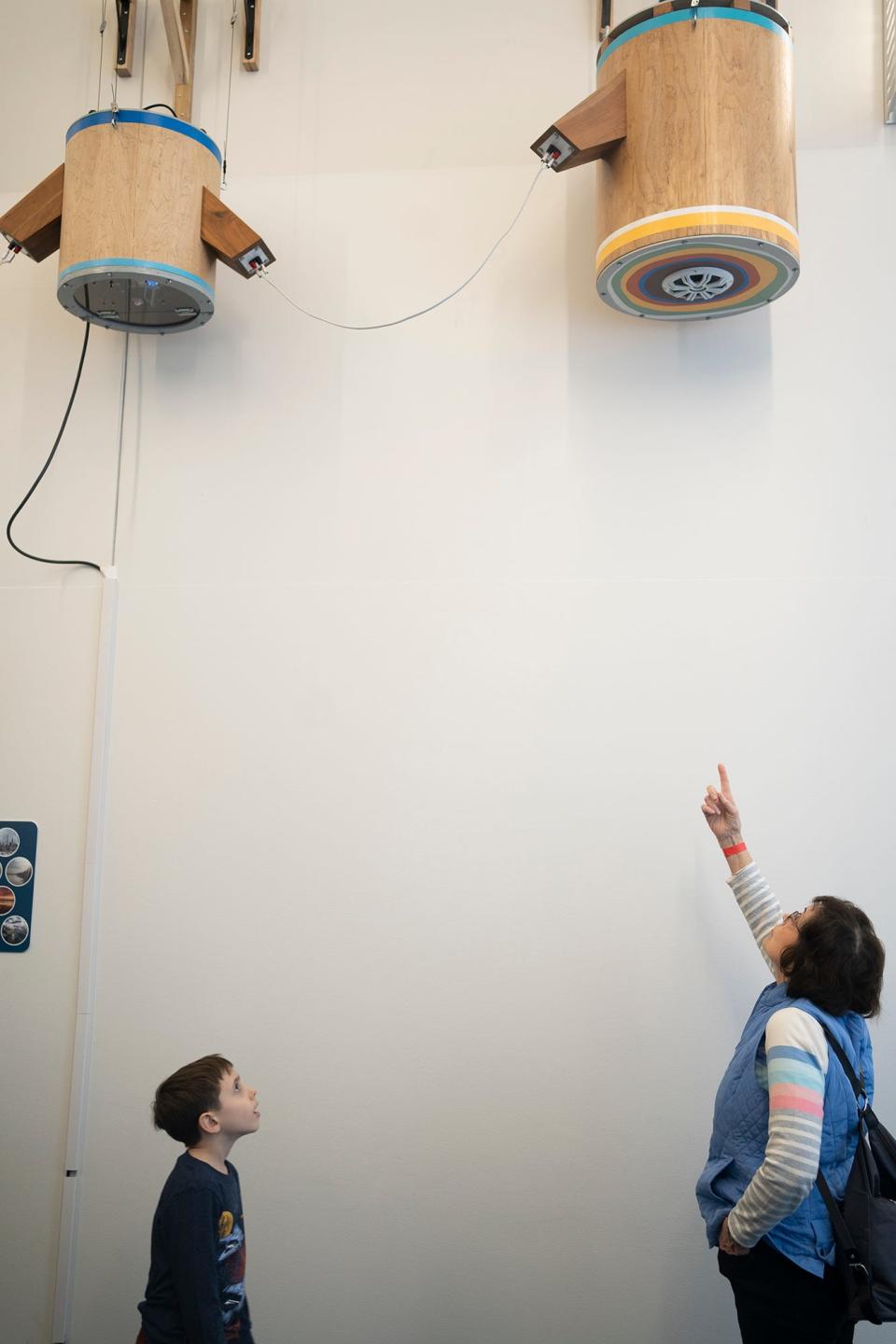 Anne Swarr Labelle, of Cincinnati, shows her grandson, Raphael Swarr, 8, the "Memory Machine" created by Columbus artist Daric Gill. The sound sculpture is on exhibit at COSI.