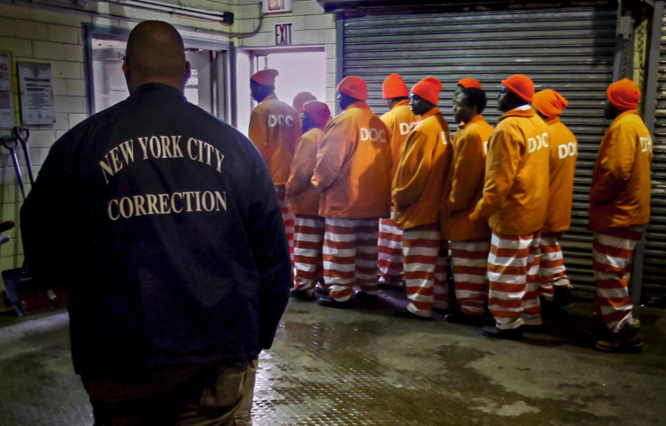 FILE - In this March 16, 2011 file photo, a corrections official watches inmates file out of a prison bakery after working the morning shift at the Rikers Island jail in New York. New York City’s notorious Rikers Island jail complex, troubled by years of neglect, has spiraled into turmoil during the coronavirus pandemic. (AP Photo/Bebeto Matthews, File)