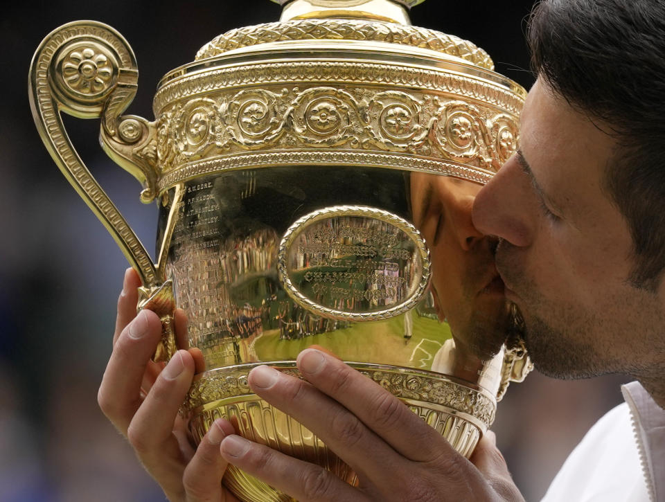 Novak Djokovic besa el trofeo de campeón tras derrotar a Matteo Berrettini en la final de Wimbledon, el domingo 11 de julio de 2021, en Londres. (AP Foto/Kirsty Wigglesworth)