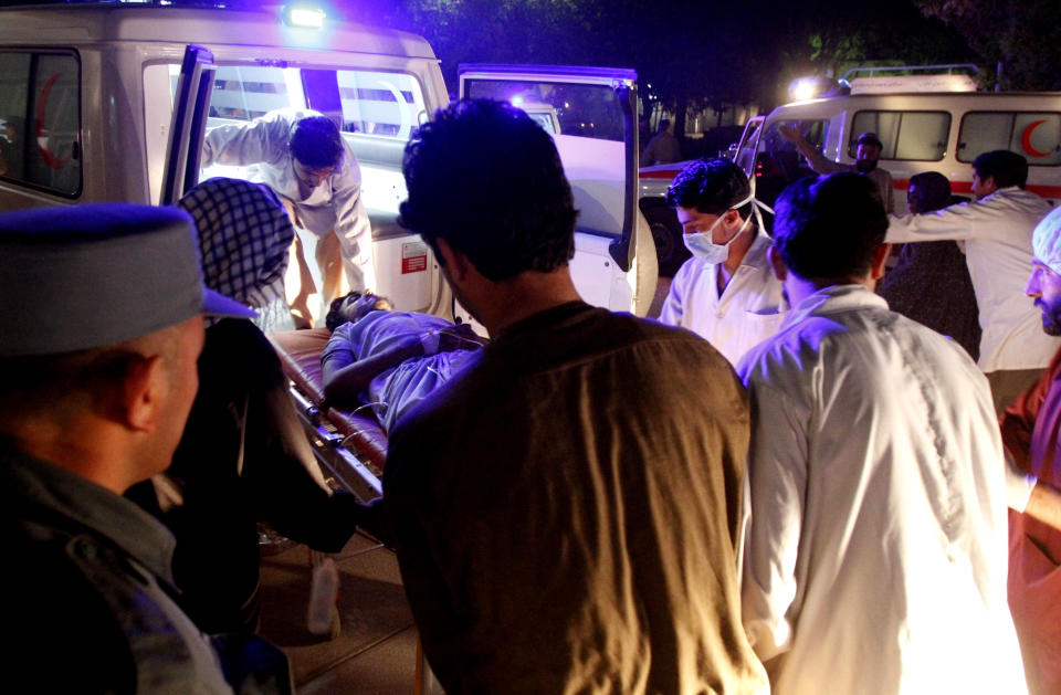 Afghan doctors, receive a wounded man from an ambulance after a roadside bomb struck, at a hospital in Kandahar, south of Kabul, Afghanistan, Monday, April 7, 2014. A roadside bomb killed at least 15 people traveling in vehicles that had been diverted from a main road Monday after an earlier attack in southern Afghanistan, officials said. (AP Photo/Allauddin Khan)