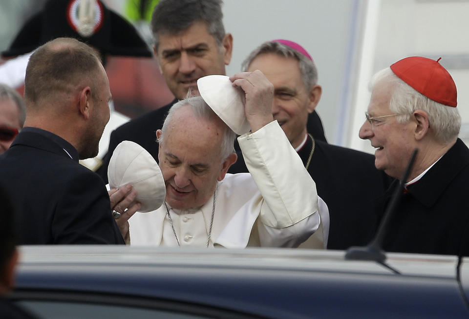 Pope Francis changes his skull cap as he arrives at Milan's Linate airport, northern Italy, for a one-day pastoral visit to Monza and Milan, Italy’s second-largest city, Saturday, March 25, 2017. On Friday Francis welcomed 27 EU leaders to the Vatican on the eve of a summit to mark the 60th anniversary of the Treaty of Rome, the founding charter of the bloc. At right the Archbishop of Milan, Cardinal Angelo Scola looks on. (AP Photo/Luca Bruno)