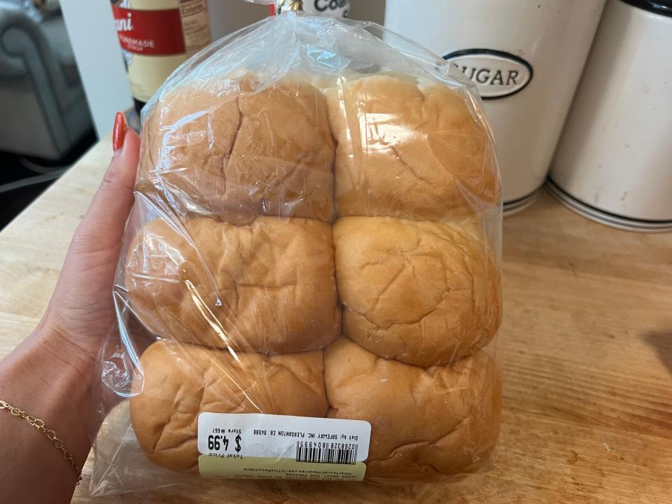 hand holding up a bag of dinner rolls from safeway