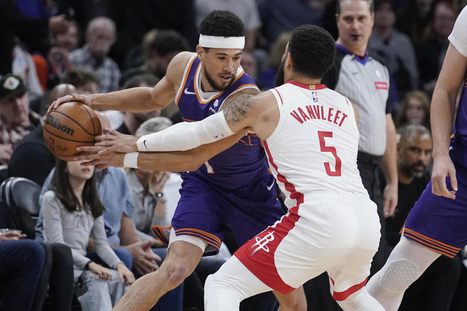 Phoenix Suns guard Devin Booker (1) keeps the ball away from Houston Rockets guard Fred VanVleet (5) during the first half of an NBA basketball game in Phoenix, Saturday, March. 2, 2024. (AP Photo/Darryl Webb)