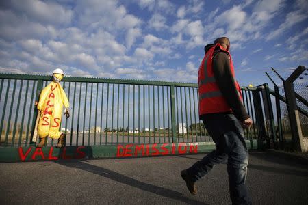 A striking employee walks near the blocked the entrance of the fuel depot of the SFDM company, with the message, "Prime Minister Valls - Resign", near the oil refinery of Donges, France, May 25, 2016 in protest over proposed new labour laws. REUTERS/Stephane Mahe