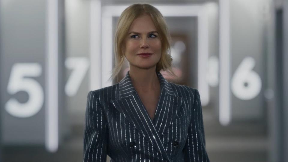 Kidman smiles as she wears a glittering striped pantsuit and wanders through a movie theater
