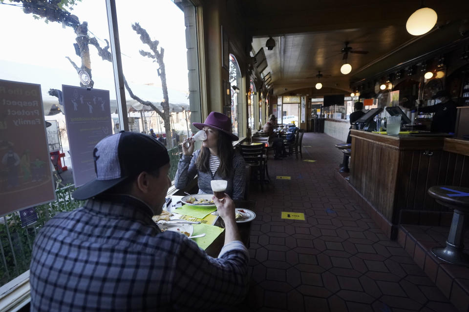 FILE - I this Nov. 12, 2020, file photo, Mitchell Bryant, left, and Darla Scott eat inside at the Buena Vista Cafe during the coronavirus outbreak in San Francisco. States in the U.S. are renewing their push for more federal money to deal with the fallout from the coronavirus outbreak and to help them distribute a vaccine when one becomes widely available sometime in 2021. Gov. Gavin Newsom this week barred indoor restaurant dining and imposed other restrictions. (AP Photo/Jeff Chiu, File)