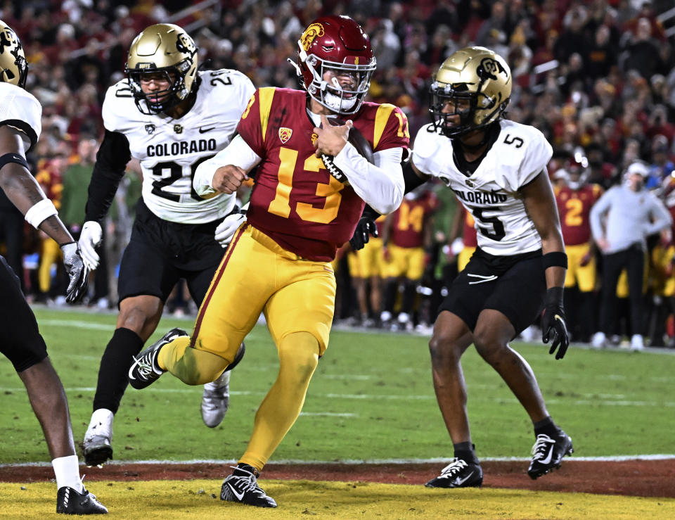 Southern California quarterback Caleb Williams scores a touchdown, getting past Colorado's Robert Barnes, left, and Tyrin Taylor during the first half of an NCAA college football game Friday, Nov. 11, 2022, in Los Angeles. (AP Photo/John McCoy)