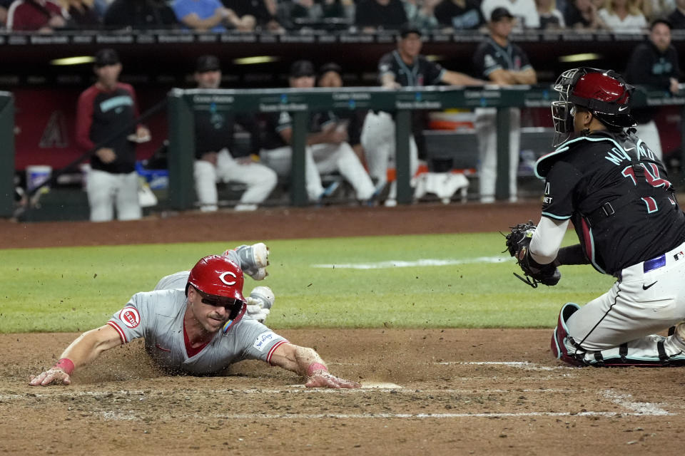 Cincinnati Reds' Spencer Steer, left, scores a run as Arizona Diamondbacks catcher Gabriel Moreno, right, makes a catch on a late throw during the eighth inning of a baseball game Monday, May 13, 2024, in Phoenix. (AP Photo/Ross D. Franklin)