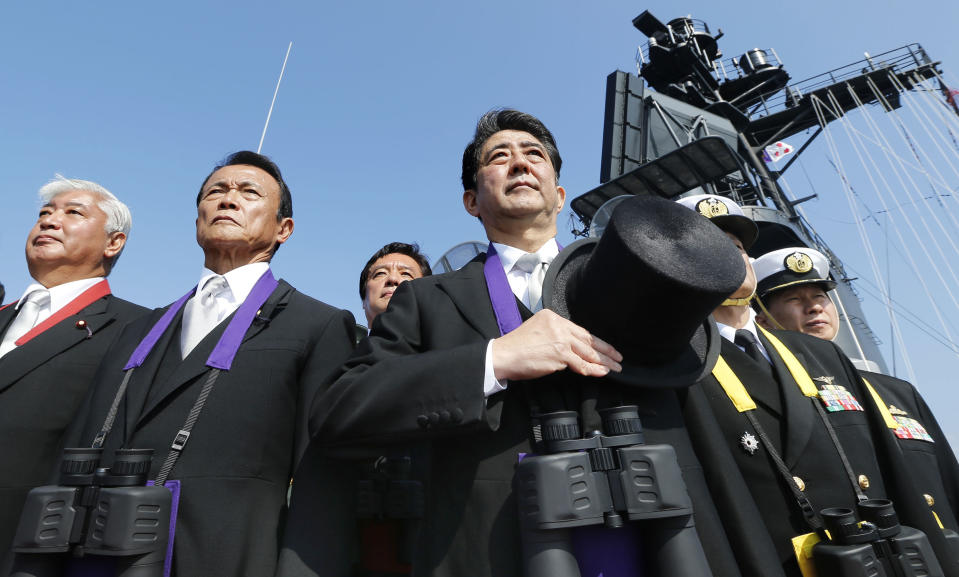 FILE - In this Oct. 18, 2015 file photo, Japanese Prime Minister Shinzo Abe, center, stands with Deputy Prime Minister and Finance Minister Taro Aso, second left, and Defense Minister Gen Nakatani, left, during the official triennial Maritime Self-Defense Force fleet review aboard the JMSDF escort ship Kurama in the waters off Sagami Bay, south of Tokyo. Emperor Akihito's words have taken on greater import as Japanese Prime Minister Abe has sought to move Japan beyond its troubled past since coming to power in December, 2012. Opponents of Abe’s policies have grabbed onto the emperor’s statements as a counterbalance to the prime minister’s push to revise Japan’s war-renouncing constitution and build up its military.(Kazuhiko Yamashita/Kyodo News via AP, File)