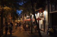 People gather outside a restaurant at night in Gracia neighborhood in Barcelona, Spain, Friday, July 24, 2020. Health authorities in the northeastern region of Catalonia have ordered nightclubs to be fully closed and bars and restaurant in Barcelona to shut down by midnight in an effort to stem the spread of the new coronavirus. (AP Photo/Felipe Dana)