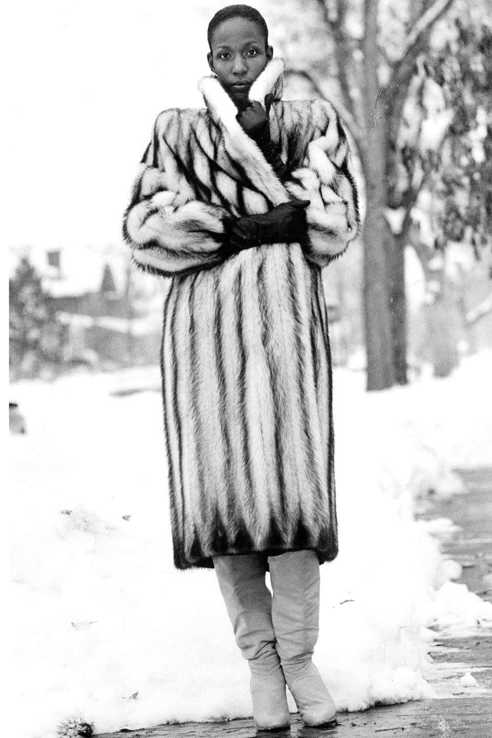 <p>A woman wears a fur coat and slouchy leather boots out in the snow. </p>