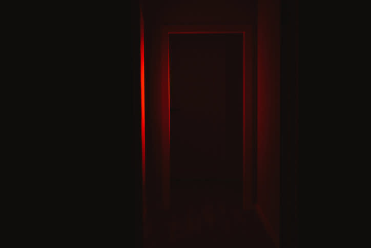 A dimly lit corridor with an illuminated exit sign at the far end