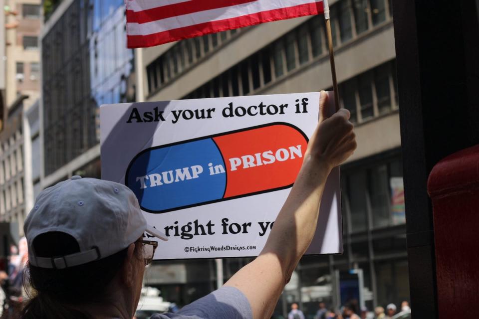 A Trump protestor holds a sign saying, “Ask your doctor if Trump in prison is right for you” outside of Trump Tower on 31 May (Ariana Baio)