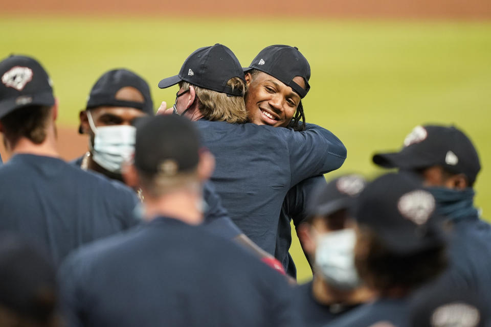 Atlanta Braves' Ronald Acuna Jr. center, hugs a coach to celebrate after a baseball game to clinch the NL East baseball title against the Miami Marlins on Tuesday, Sept. 22, 2020, in Atlanta. (AP Photo/Brynn Anderson)