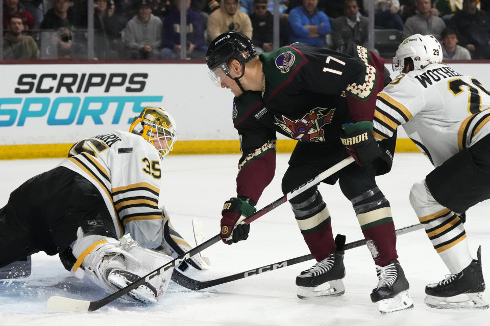 Boston Bruins goaltender Linus Ullmark (35) makes a save on a shot by Arizona Coyotes center Nick Bjugstad (17) as Boston Bruins defenseman Parker Wotherspoon (29) applies pressure during the first period of an NHL hockey game Tuesday, Jan. 9, 2024, in Tempe, Ariz. (AP Photo/Ross D. Franklin)