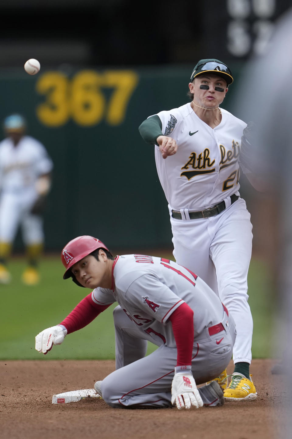Oakland Athletics second baseman Zack Gelof, top, throws to first base after forcing Los Angeles Angels' Shohei Ohtani, bottom, out at second base on a double play hit into by Brandon Drury during the fifth inning of a baseball game in Oakland, Calif., Saturday, Sept. 2, 2023. (AP Photo/Jeff Chiu)