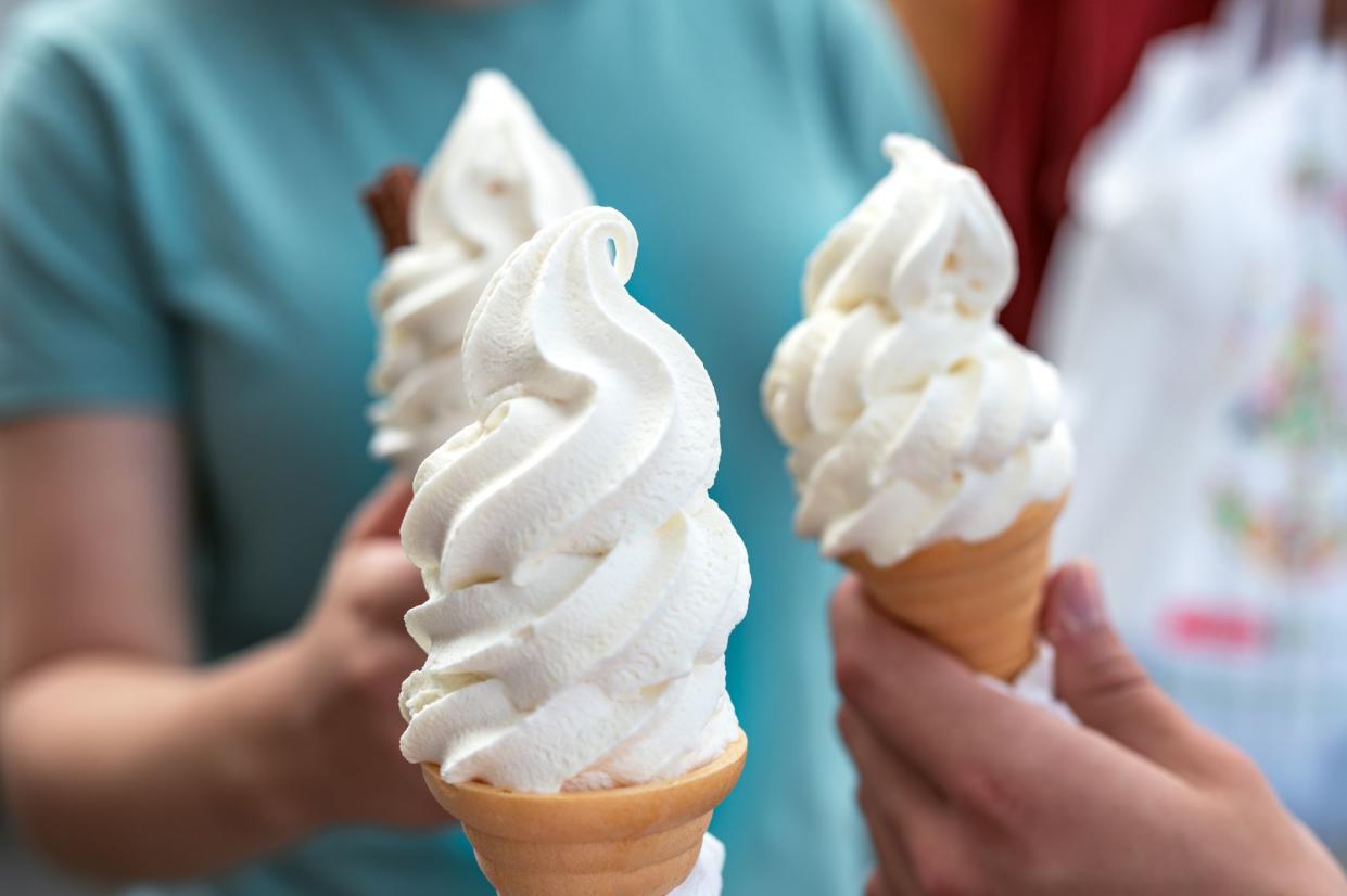 Several soft vanilla ice creams with chocolate sticks in hands